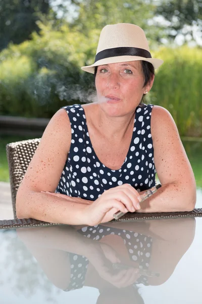 Siiting atrakcyjna kobieta przy basenie i palenia e papierosów — Zdjęcie stockowe