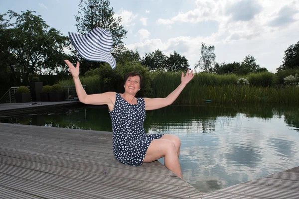 Aantrekkelijke vrouw siiting met benen in het zwembad en het gooien van haar — Stockfoto