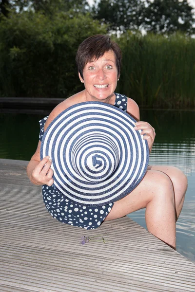 Aantrekkelijke vrouw siiting met benen in het zwembad en de behin verbergen — Stockfoto