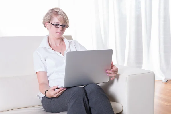 Молодая привлекательная женщина работает с ноутбуком на диване — стоковое фото
