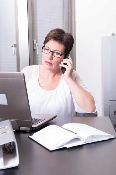 Mulher em seu escritório de casa no telefone — Fotografia de Stock