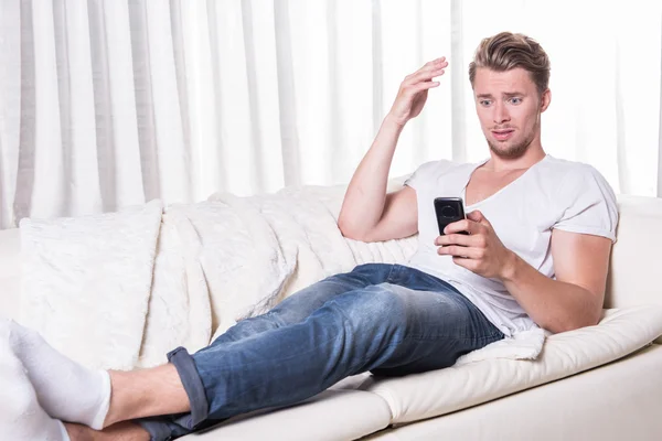 Młody człowiek jest przerażony o wiadomość na smartphone — Zdjęcie stockowe