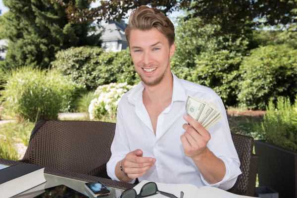 Unga företag man räknar dollar i trädgården — Stockfoto