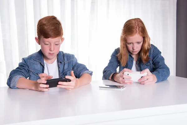 iki redhaired çocuk onların akıllı telefonlar ile oynuyorlar