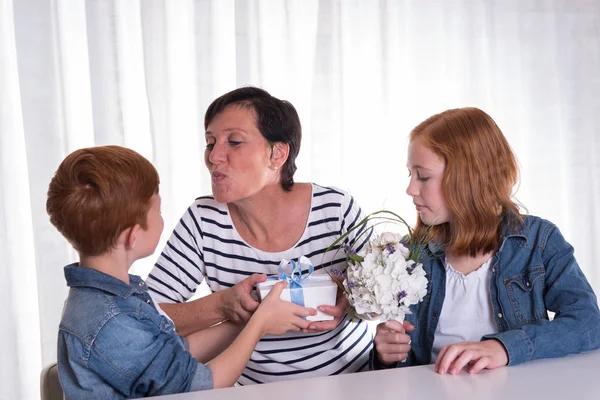 Två rödhårig barn ger en present till sin mamma — Stockfoto