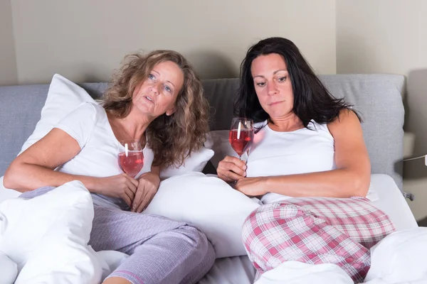 Duas mulheres atraentes tomando uma bebida na cama — Fotografia de Stock