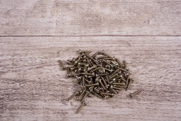 Veel messing schroeven liggend op houten tafel-close-up — Stockfoto