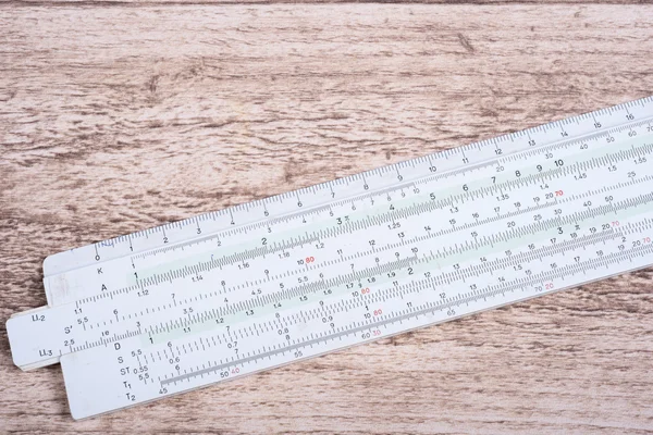 Historic slide rule lying on wooden table — Stock Photo, Image