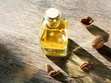 Bir şişe ceviz yağı ve ceviz, eski, siyah ahşap bir masada.