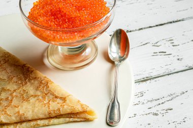 Geleneksel Rus yemekleri: buğday unundan yapılmış krepler ve beyaz bir masada kırmızı havyar.