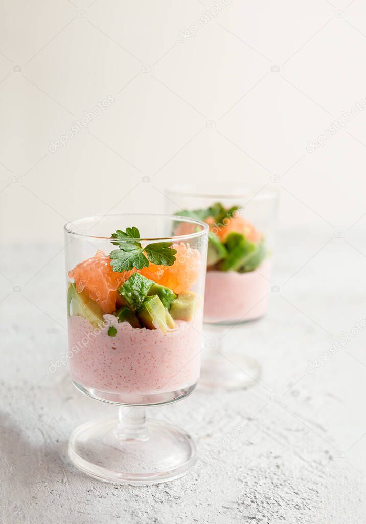 Tarama or taramasalata appetizer with avocado and pink grapefruit in glass cups on the light gray background close-up