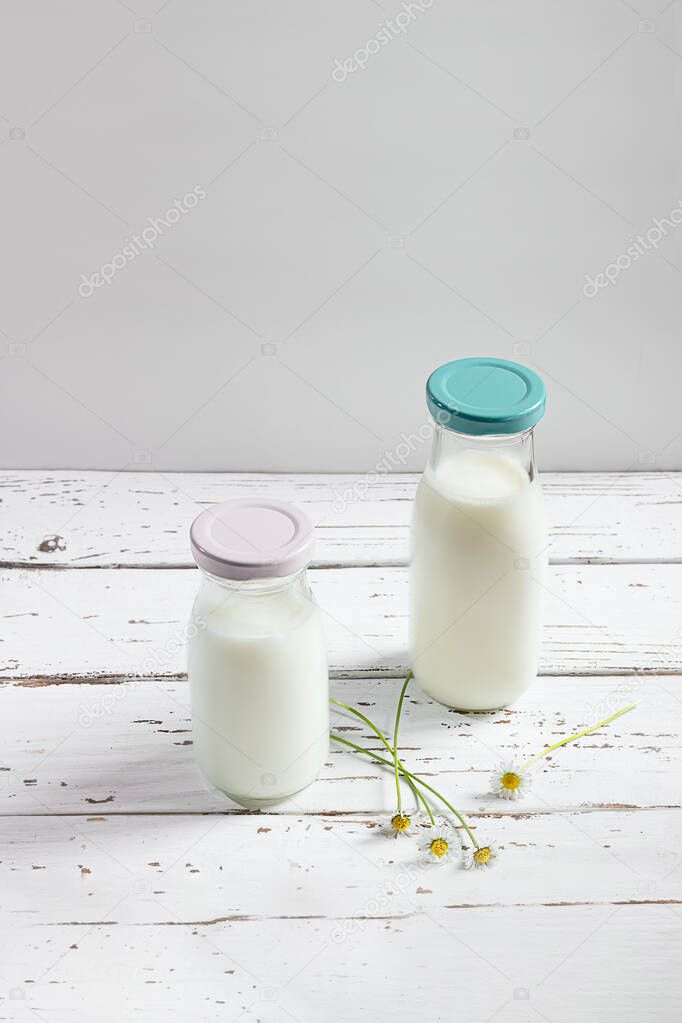 Two bottles with fresh organic dairy product on a white wooden table