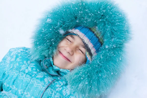 Happy kid girl child outdoors in winter lying on snow under snow — Stock Photo, Image