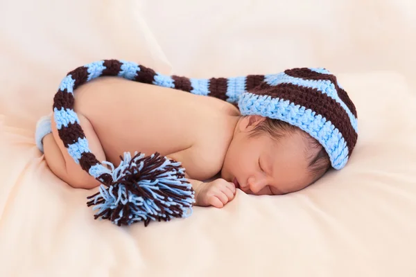 Newborn in knitted hat on beige background — Stock Photo, Image