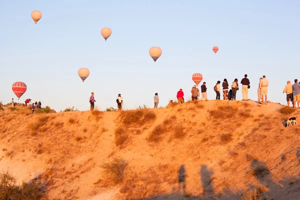 Grupo de turistas viendo volar globos en la cima de la montaña —  Fotos de Stock