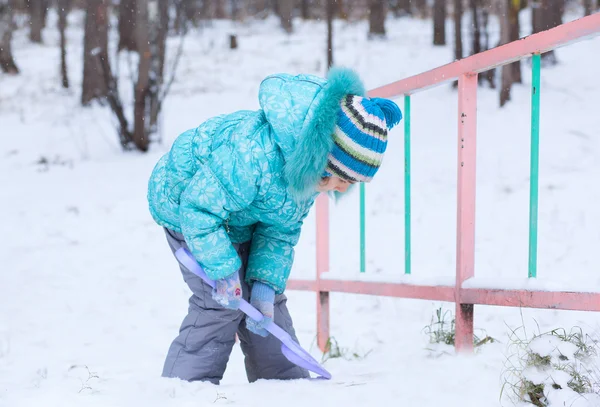Happy kid girl child outdoors in winter digging snow with toy sp — Stock Photo, Image