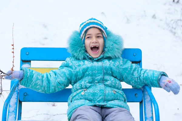 Happy kid girl child outdoors in winter sitting on bench — Stock Photo, Image