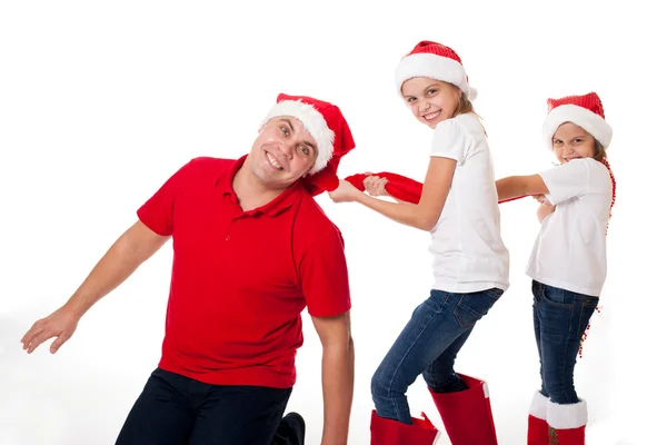 Pai feliz e duas filhas nos chapéus do Papai Noel rindo — Fotografia de Stock