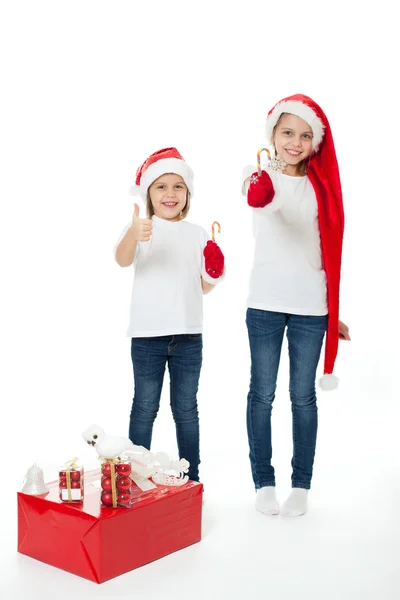 Irmãs felizes nos chapéus do Papai Noel com presentes de Natal — Fotografia de Stock