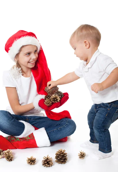 Irmã mais velha do chapéu do Pai Natal a brincar com o irmão mais novo — Fotografia de Stock