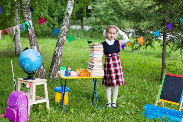 Školačka dítě dítě dívka drží obrovský balení knih s ní — Stock fotografie