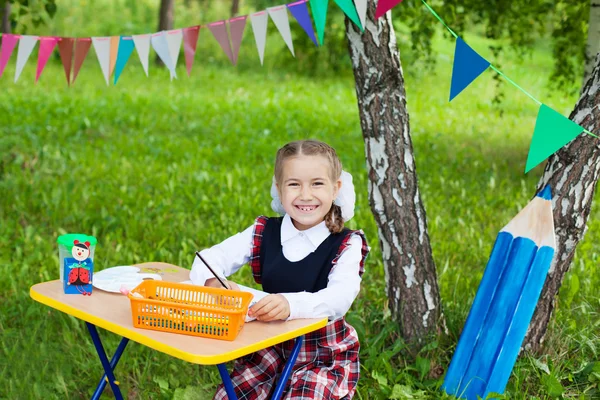 Niño colegiala feliz niña sentada en la mesa y la escritura, cl — Foto de Stock