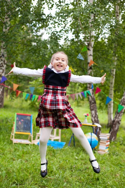 Happy schoolgirl child kid girl jumping and smiling, classroom o — Stock Photo, Image