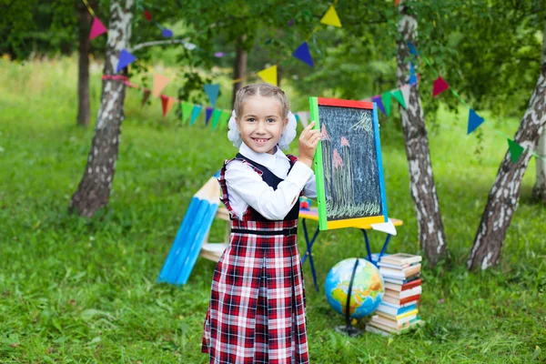 Happy schoolgirl child kid girl holding chalkboard with drawing — Stock Photo, Image