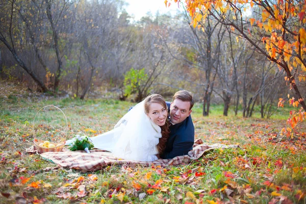 Happy wedding couple in autumn winter forest, lying on plaid hug — Stock Photo, Image