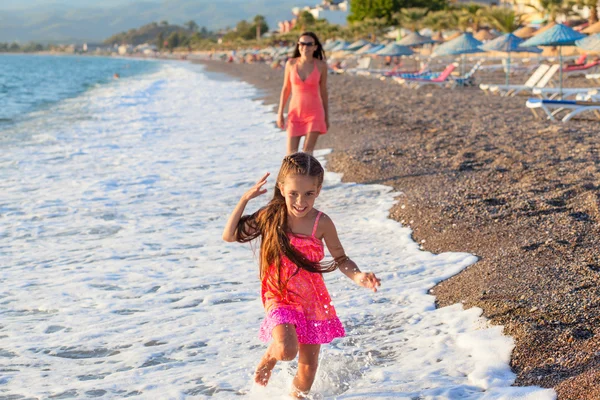 Mamma och hennes lilla dotter spelar och kör på stranden — Stockfoto