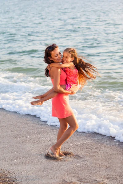 Mamma och hennes lilla dotter spelar och kör på stranden — Stockfoto