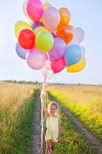 Happy little girl child kid with balloons outdoors on sky and fi — Stock Photo, Image