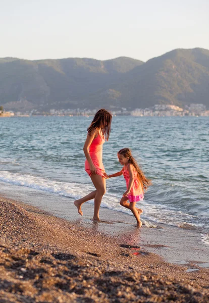 Mamma och hennes lilla dotter spelar och kör på stranden — Stockfoto