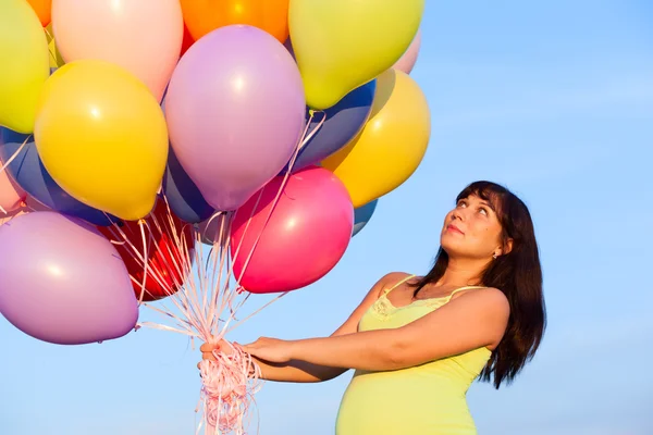 Hermosa chica embarazada joven feliz al aire libre con globos —  Fotos de Stock