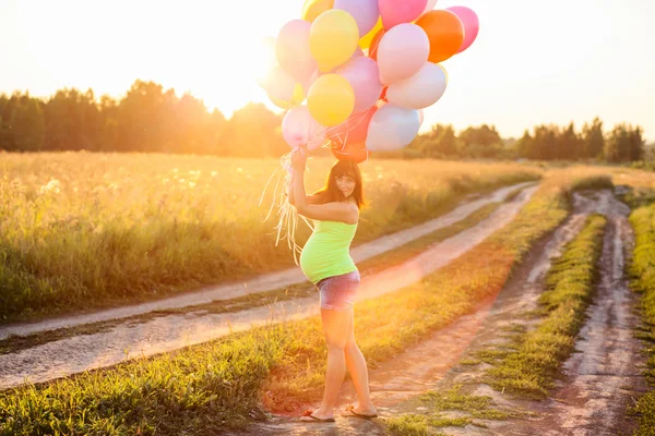 Hermosa chica embarazada joven feliz al aire libre con globos — Foto de Stock