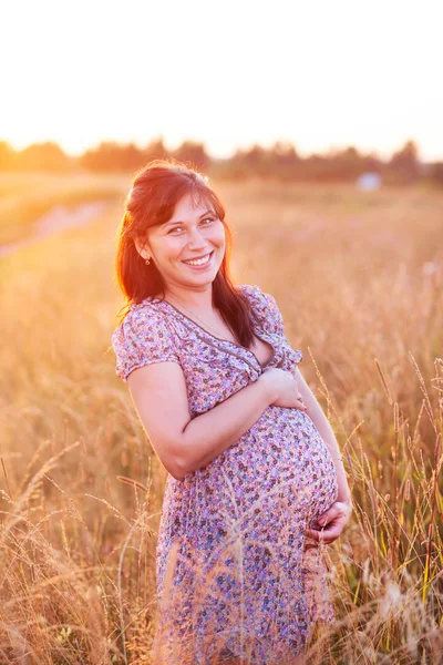 Beautiful happy young pregnant woman girl in field, smiling and Royalty Free Stock Images