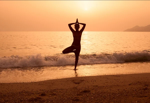 Silhouette d'une fille pratiquant le yoga sur la plage de la mer — Photo