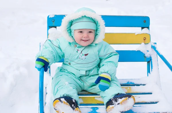 Baby boy sitting on bench in park in winter — Stock Photo, Image