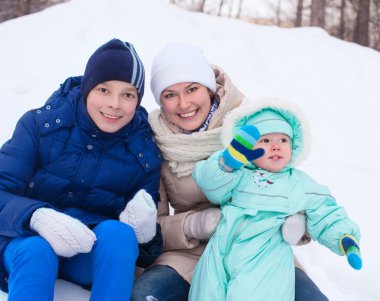 Happy family mother and baby and teenager in winter park