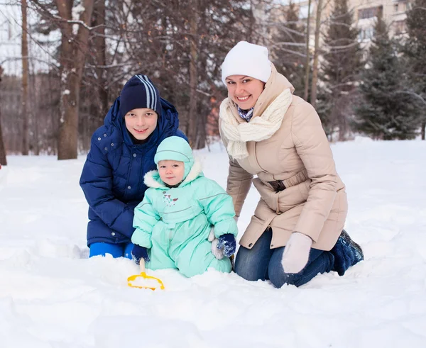 Happy family mother and baby and teenager in winter park — Stock Photo, Image