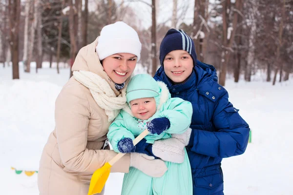 Happy family mother and baby and teenager in winter park — Stock Photo, Image