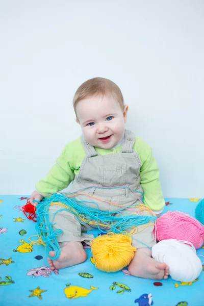 Симпатичный улыбающийся ребенок, играющий с вязанием — стоковое фото