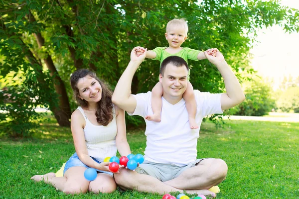 Gelukkige familie spelen met kleurrijke ballen in park — Stockfoto