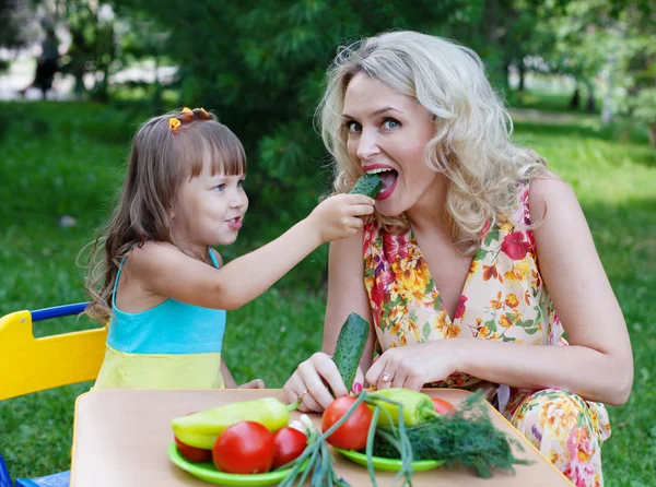 Meisje dochter kind kind moeder moeder vervoederen komkommer buiten — Stockfoto