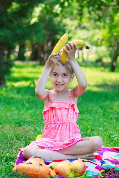 Little beautiful girl child kid sitting on grass with bananas — Stock Photo, Image