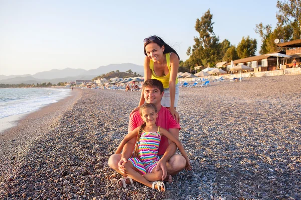 Zittend op kussen poseren op strand zonsondergang en gelukkige familie — Stockfoto