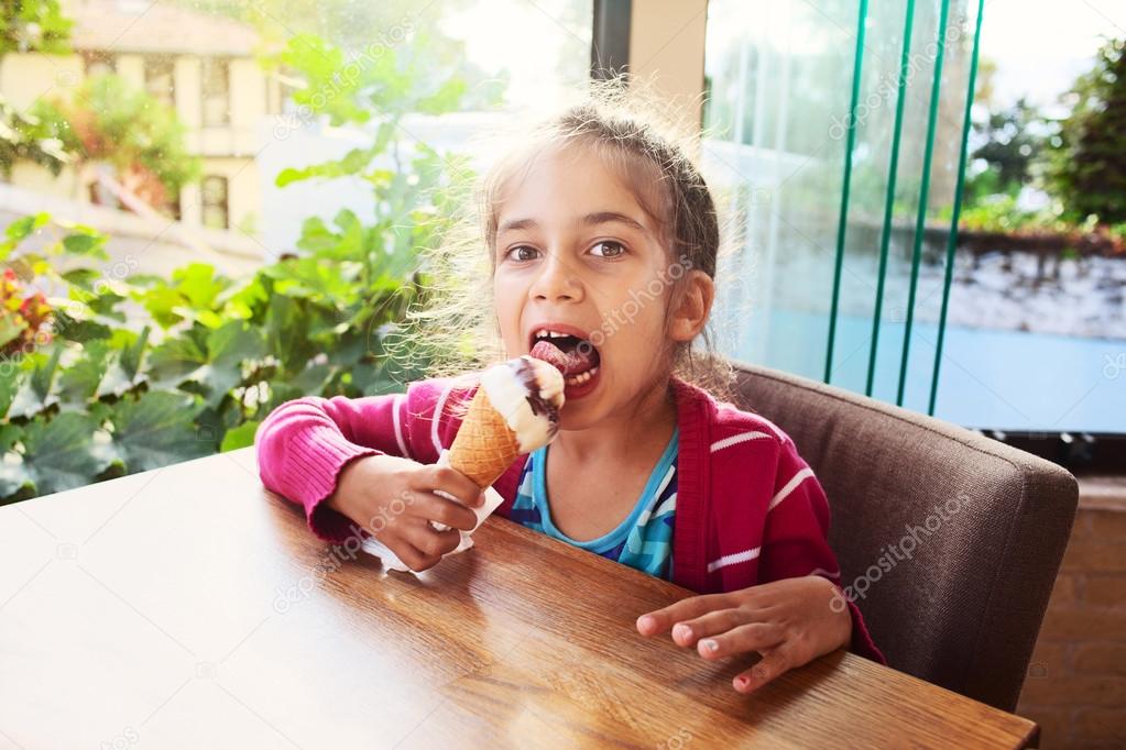 Happy little girl child kid chocolate eating ice cream in cafe