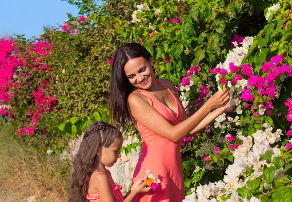 Kobieta z dzieckiem dziecko dziewczynka na tle bougainvillaea — Zdjęcie stockowe