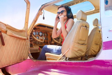 Pilot girl in cabin of little plane clipart