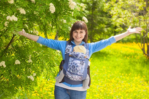 Newborn baby and mother outdoors walking with sling. — Stockfoto